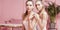 Beautiful caucasian twins female models on pink background.