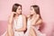 Beautiful caucasian twins female models on pink background.