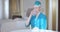 Beautiful Caucasian woman drinking water in hotel room. Portrait of confident female flight attendant in blue stewardess