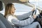 Beautiful caucasian woman driving holding a cup of coffee.Female sitting in her car with cardboard cup coffee to go in hands