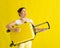 Beautiful caucasian woman fooling around with a suitcase on a yellow background. A charming girl imitates playing the