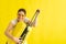 Beautiful caucasian woman fooling around with a suitcase on a yellow background. A charming girl imitates playing the