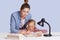 Beautiful Caucasian woman helping her doughter to do school homework, mother and child surronded by books, little girl sitting