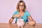 Beautiful caucasian woman holding piggy bank with glasses puffing cheeks with funny face