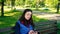 Beautiful Caucasian woman with long brown hair sitting on a yoga mat in the park drinking a cup of tea or coffee and smiling.