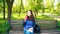 Beautiful Caucasian woman with long brown hair sitting on a yoga mat in the park drinking a cup of tea or coffee and smiling.