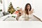 Beautiful caucasian woman sitting on the table by christmas tree afraid and terrified with fear expression stop gesture with