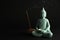 Beautiful ceramic Buddha sculpture with burning candle and incense stick on black background. Space for text