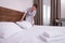 Beautiful chambermaid making bed in hotel room
