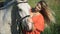 A beautiful charming blonde woman walking with a horse at a field