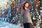 Beautiful charming girl with red hair in the winter park. Pensive, dreamy, loving look. Cold weather. Trees in the snow