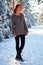 Beautiful charming girl with red hair in the winter park. Pensive, dreamy, loving look. Cold weather. Trees in the snow