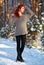 Beautiful charming girl with red hair in the winter park. Pensive, dreamy, loving look. Cold weather. Trees in the snow