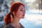 Beautiful charming girl with red hair in the winter park. Pensive, dreamy, loving look. Cold weather. Trees in the snow