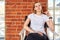 Beautiful cheeky young girl is sitting in a chair by the brick wall. Background brick brick, copy space