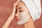 Beautiful cheerful Asian teen girl applying facial clay mask. Beauty treatments, isolated on light background