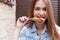 Beautiful cheerful cute red-haired girl eating colored ice cream on city streets