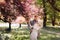 Beautiful, cheerful and lively newlyweds, groom and bride are hugging near the blooming pink cherry blossom. Wedding portrait of a