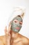 Beautiful cheerful teen girl applying facial clay mask. Beauty treatments, isolated over white