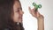 Beautiful cheerful teen girl playing with green fidget spinner on white background stock footage video