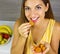 Beautiful cheerful young woman eating delicious dehydrated apricots at home. Close up from above. Healthy concept