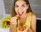 Beautiful cheerful young woman eating delicious dehydrated apricots at home. Close up from above. Healthy concept