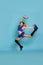 Beautiful cheerleader with pom poms jumping on light blue background