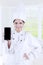 Beautiful chef shows mobile phone in kitchen