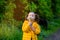 Beautiful child girl with ponytails in a yellow jacket holds white fluffy dandelions and smiles