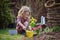 Beautiful child girl in spring garden plays and planting hyacinth flowers