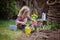 Beautiful child girl in spring garden plays and planting hyacinth flowers