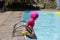 Beautiful child learning to swim in the pool with a pink float.