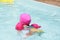 Beautiful child learning to swim in the pool with a pink float.