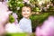 Beautiful child in pink flowers, little boy smile in summer