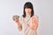 Beautiful chinese woman holding bowl with sunflowers seeds over isolated white background with open hand doing stop sign with