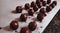Beautiful chocolate truffles dipped in melted chocolate mass and sparkled with cocoa powder on a baking white paper on a marble