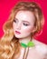 A beautiful choker made of gold chains and green fluff around the neck of a red-haired girl. Woman posing on red