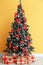 Beautiful Christmas tree with gifts near color wall