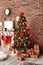 Beautiful Christmas tree and gifts near fireplace with stockings indoors