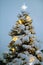 Beautiful Christmas tree with toys and a star on top in the snow photographed