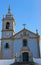 Beautiful church with azulejo tiles on sunny day in Portugal. Catholic cathedral with bell and cross and clock. Dome with steps.