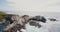 Beautiful cinematic aerial shot of idyllic ocean waves crashing over large rocks at summer Big Sur coast California.