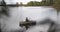 Beautiful cinematic shot. Girl fisherman rowing oars on lake an inflatable boat.