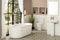 Beautiful classic bathroom interior with white bathtub, pedestal sink with a mirror, and toilet