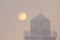 A beautiful close-up photo of the lighthouse against the backdrop of a pink sky and a huge sun. Cityscape of Murmansk - a city in