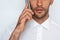 Beautiful close-up portrait of young man using mobile phone on gray background. Businessman speaking on his smart phone.