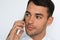 Beautiful close-up portrait of young man using mobile phone on gray background. Businessman speaking on his smart phone.