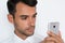 Beautiful close-up portrait of young man using mobile phone on gray background. Businessman speaking on his smart phone.