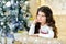 Beautiful close up portraite of curly girl with gold Christmas garlands magic lights and tree decorations gift box