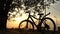 Beautiful close up scene of bicycle at sunset, sun on blue sky with vintage colors, silhouette of bike forward to sun.